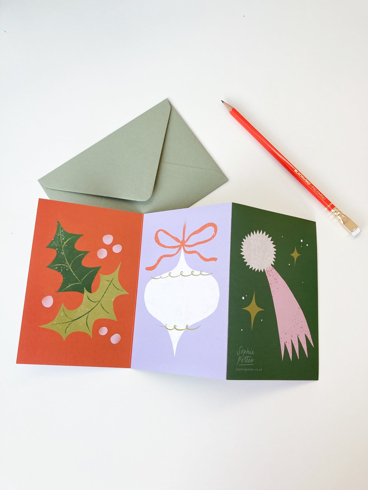 Art concertina christmas card featuring holly, bauble and shooting star.
